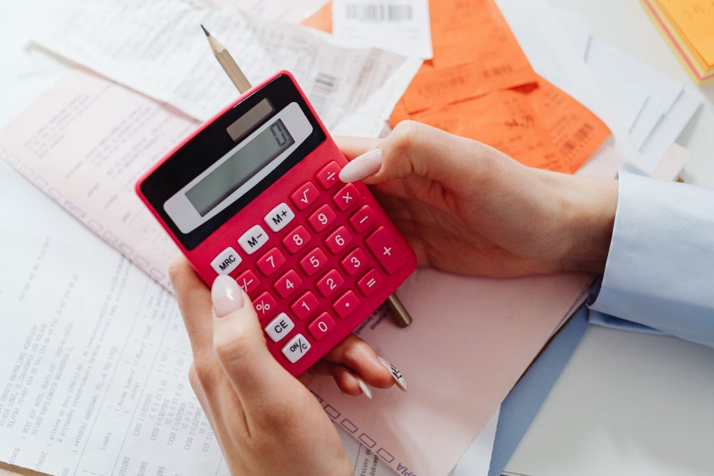 Auto-entrepreneur calculant ses cotisations sociales avec une calculatrice et ses factures