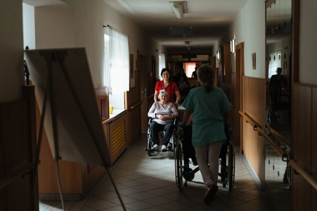Une aide-soignante accompagne une résidente âgée en maison de retraite